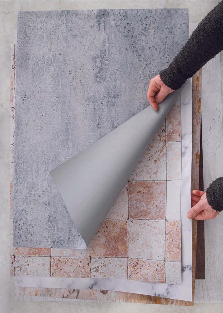 Mani che sollevano gli sfondi fotografici in vinile per far capire che sono arrotolabili e leggeri