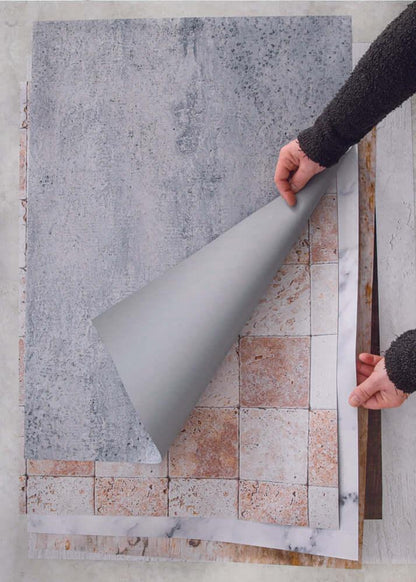 Mani che sollevano gli sfondi fotografici in vinile per far capire che sono arrotolabili e leggeri