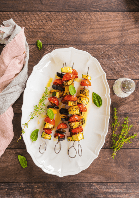 Scatto flatlay di piatto ovale con spiedini di verdure su sfondo a doghe orizzontali in legno scuro e rustico