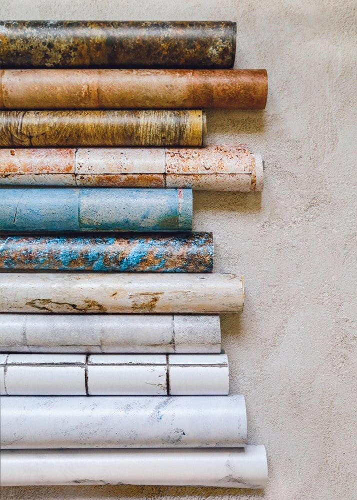 Sfondi fotografici in vinile arrotolati e disposti uno sopra l'altro in verticale fotografati in flatlay