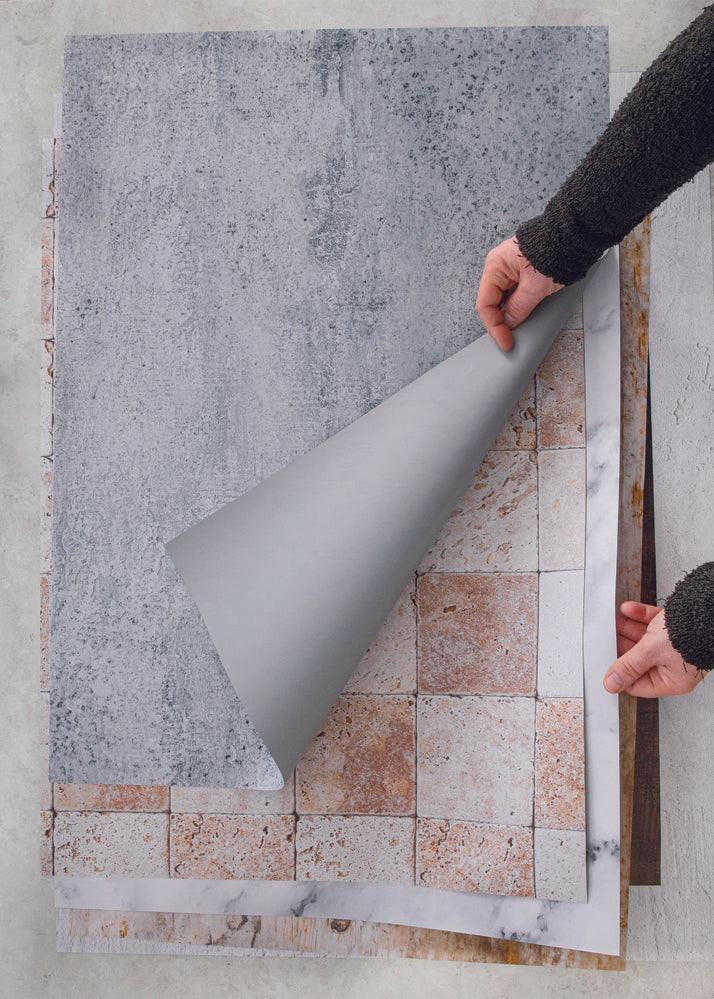 Mani che sollevano gli sfondi fotografici in vinile per far capire che sono arrotolabili e leggeri